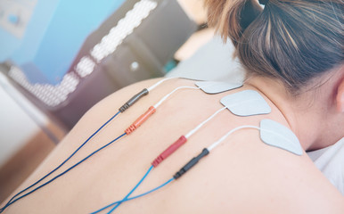 Physical therapist positioning electrodes for high back muscle treatment