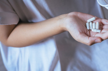 Female hand holding a medicine,Woman hands with pills on spilling pills out of bottle
