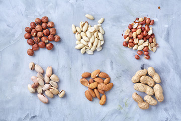 Three wooden bowls of unpeeled peanuts over rustic wooden background closeup, selective focus