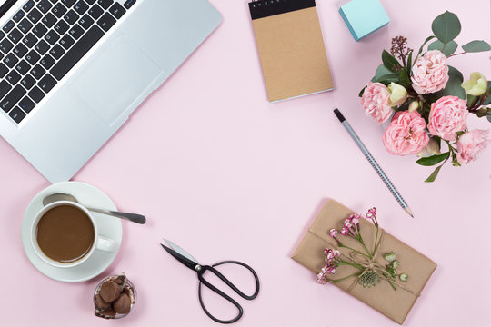 Top View Of Pink Office Desk Table With Laptop, Smartphone, Cup Of Coffee And Flowers. Copy Space, Flat Lay.