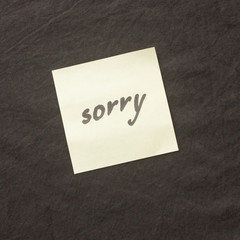 Handwritten note on a dark background. Note of apology- Sorry, please forgive me.