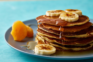 Pile of homemade pancakes with honey and walnuts on blue background, selective focus