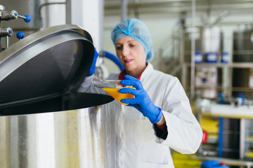 Worker at bottling factory checking juice quality. 