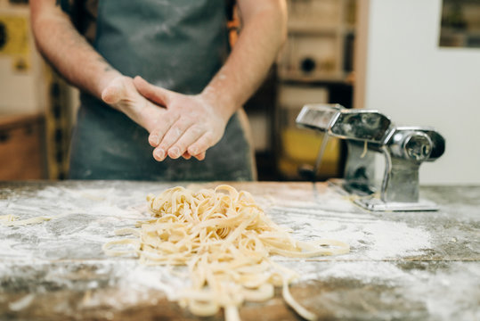 Chef against table with fettuccine, pasta machine