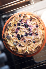 Raw vegan sweet tart, pie or cake with blueberries currants, coconut, dates, bananas, oil, cocoa powder and cashew cream on a silicone plate in the oven . Organic product.