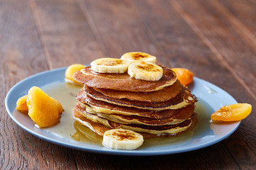 Pile of homemade pancakes with honey and walnuts on blue background, selective focus