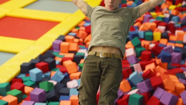a young man with a sporty physique jumps down into inflatable squares, the person feels free falling during a jump back on toy blocks