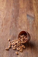 Ceramic bowl of almonds on wooden background, top view, close-up, selective focus.