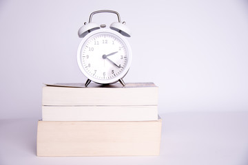 clock standing on the books on a white background