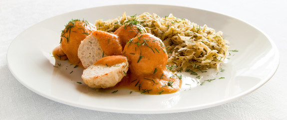 a plate of braised cabbage with porcupine meatballs poured with vegetables sour cream sauce