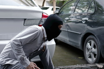 Thief in black balaclava trying to break into car