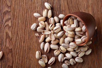 Almonds in brown bowl on wooden background, top view, selective focus.