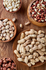 A composition from different varieties of nuts in a wooden bowls on rustic background, close-up, shallow depth of field