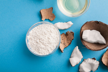 Plate with coconut flour and nuts on blue background