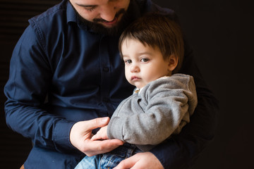 Father holding hand of small pensive boy