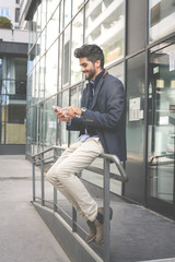 Businessman on street typing on mobile phone.