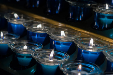 Many Blue Wax Candle in Glass. Close-up. Candle light in a straight glass jar.