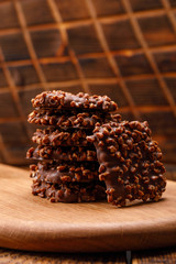 Chocolate chip cookies stacked up on a wooden board in low light. Close-up.
