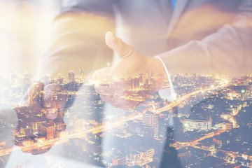 Double Exposure of a businessman handshake on the background blurred downtown nightlife. Concept of an agreement green energy.