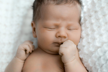 newborn sleeps on a white plaid
