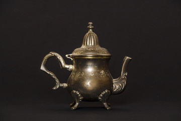 Silver antique teapot on a black background. A beautiful antique silver teapot. The kettle is silver.
