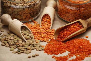 Lentils seeds on a wooden table with sackcloth. Seeds of red and green dietary supplements of lentils. Useful lentils of the legume family.