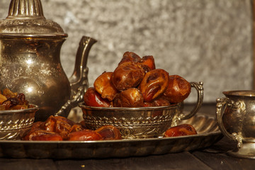 Dried dates on a wooden table in silver dishes close-up. Dates dried dried fruits in the diet chelovenka. Dates.
