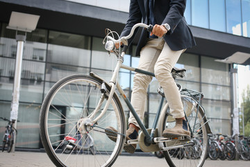 Businessman driving bike on street. Close up.