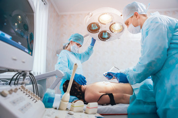 Surgeon and assistant in operating room with surgery equipment.
