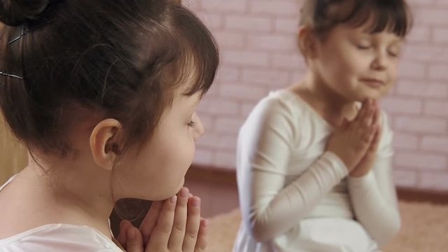 The child prays. The little girl in front of the mirror prays.
