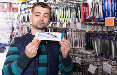 Young man customer  buying new fishing lures