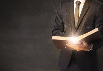 Man holding and reading a shiny book.