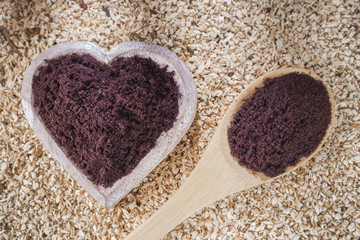 Acai powder in bowl on wooden background