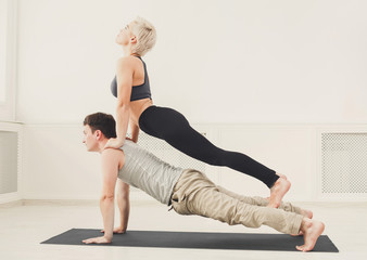 Young couple practicing acroyoga on mat together