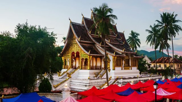 Luang Prabang, Laos. Famous night market in Luang Prabang, Laos with illuminated temple and sunset sky. Time-lapse at night, zoom in