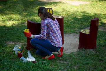 Summer. Beautiful young girl paints a wooden garden table and chairs