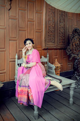 pretty woman with thai dress sit on big wooden chair in thai wooden old style house