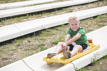 Cute smiling young boy riding downhill on an alpine coaster ride outdoors on a summers day. Happy...