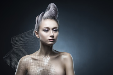 Conceptual portrait of beautiful naked shoulders vanguard hairstyle metallic colour hair girl wearing steel construction armature mesh