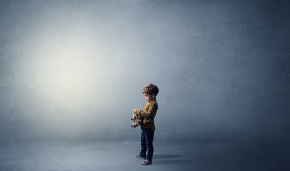 Little waggish kid staying alone in a big empty room with his plush
