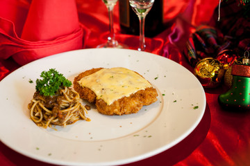 Chicken cheese with spaghetti on dish.