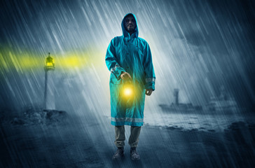Fototapeta premium Man at the coast coming in raincoat with glowing lantern concept 