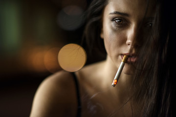 woman with a cigarette in his lips on a dark background