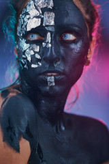 Body art glowing in ultraviolet light, creative painting on face