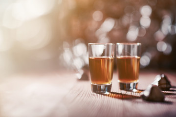 Whiskey shots on wooden background of beautiful golden light and blur