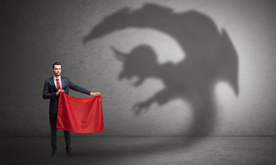 Businessman standing with red cloth in his hand and imp shadow on the background
