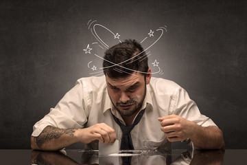 Young drunk man at his office with doodles around
