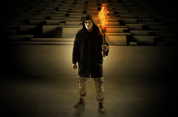 Ugly, aberrant man coming out from the labyrinth with burning flambeau on his hand
