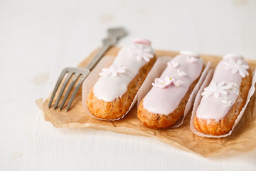 Traditional french eclairs on white table with pink flower. Copyspace