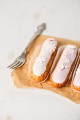 Traditional french eclairs on white table with pink flower. Copyspace
